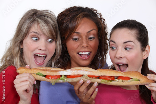 Foto: A group of friends eating a long sandwich A group of friends eating a long sandwich
