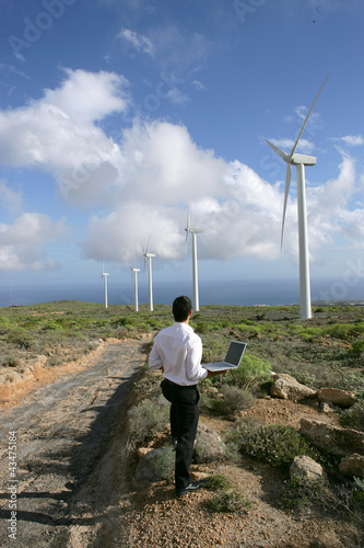 Photo: Entrepreneur with laptop observing wind turbines Entrepreneur with laptop observing wind turbines