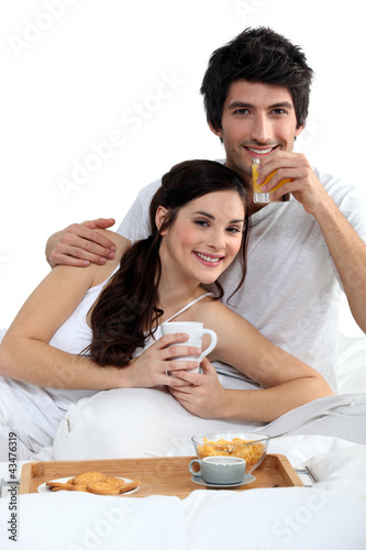 Photo: Young couple having a breakfast in bed Young couple having a breakfast in bed