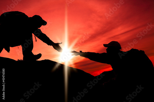 Photo: Silhouette of helping hand between two climber Silhouette of helping hand between two climber