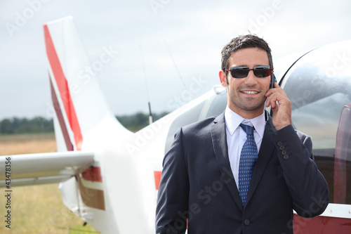Photo: Man talking on a mobile phone next to a private plane Man talking on a mobile phone next to a private plane