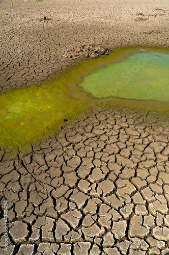 Photo: Polluted water and cracked soil of dried out lake during drought Polluted water and cracked soil of dried out lake during drought