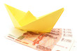 Yellow paper ship upon ruble notes isolated over white