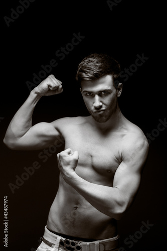 Photo: young muscular man with a bare chested on black. young muscular man with a bare chested on black.