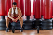 Handsome muscular man sitting in front of red punching bags.