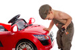 petit mécanicien penché sur sa voiture rouge