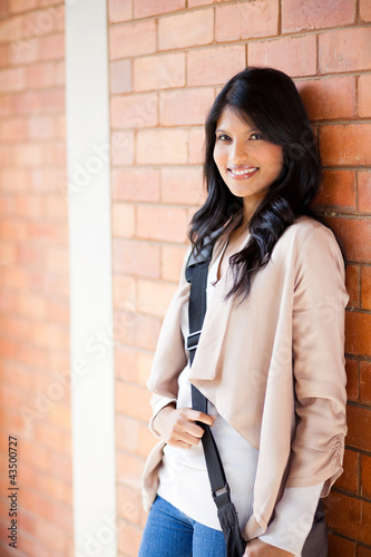 Photo: attractive female college student standing by the wall attractive female college student standing by the wall