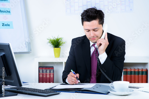 Photo: manager macht sich notizen beim telefonieren manager macht sich notizen beim telefonieren