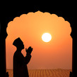 silhouette of a muslim male praying on the desert