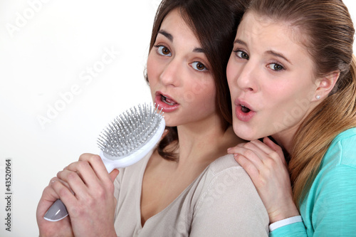 Photo: Two girl singing into hairbrush Two girl singing into hairbrush