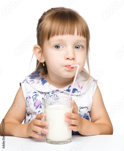 Photo: Cute little girl drinks milk using drinking straw Cute little girl drinks milk using drinking straw