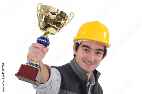 Photo: Young tradesman holding up a trophy Young tradesman holding up a trophy