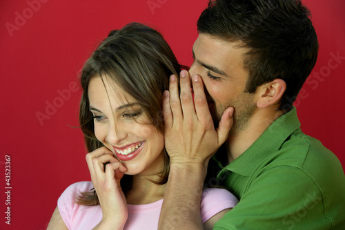 Foto: Man telling secret to woman Man telling secret to woman