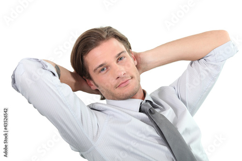Photo: Young businessman sitting with arms behind head. Young businessman sitting with arms behind head.