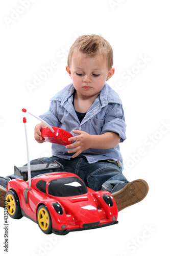 Foto: Cute little boy playing with a remote controlled car. Cute little boy playing with a remote controlled car.