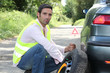 Man changing a tyre at the side of the road