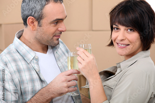 Photo: Couple drinking champagne in front of a pile of cardboard boxes Couple drinking champagne in front of a pile of cardboard boxes