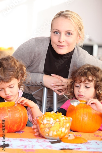 Photo: Woman helping her children carve pumpkins Woman helping her children carve pumpkins
