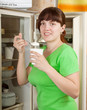 woman near opening fridge eating yoghurt