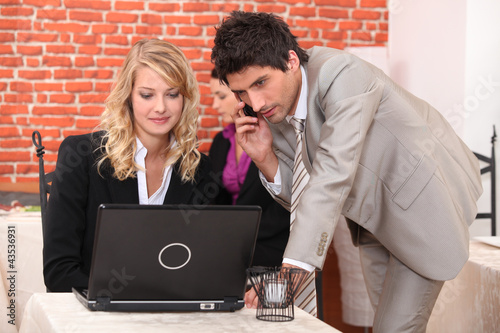 Photo: Man on a cellphone and a woman on a laptop Man on a cellphone and a woman on a laptop