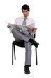 A businessman reading a newspaper on a chair.