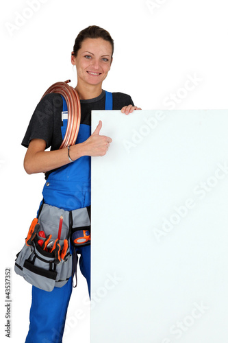 Foto: Female plumber with a board left blank for your message Female plumber with a board left blank for your message