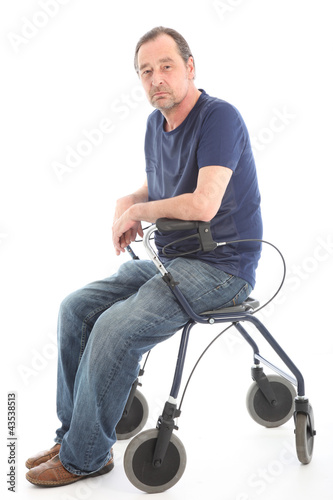 Photo: Depressed man sitting on medical walker Depressed man sitting on medical walker