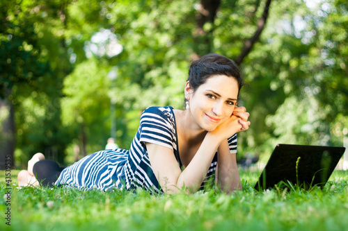Photo: Beautiful young woman using her laptop outdoors Beautiful young woman using her laptop outdoors