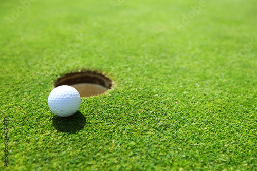 Photo: golf ball on lip of cup golf ball on lip of cup