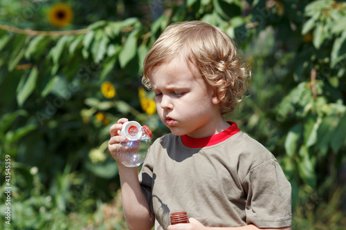 Foto: Little cute boy playing with bubbles outdoors on a sunny day Little cute boy playing with bubbles outdoors on a sunny day