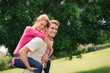Photo: young couple running piggyback in city park young couple running piggyback in city park