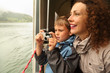 Mother with her son float at passengers vessel, boy makes photo