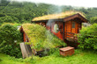 Foto: Norwegian wooden house on hill, smoke rises from forest Norwegian wooden house on hill, smoke rises from forest