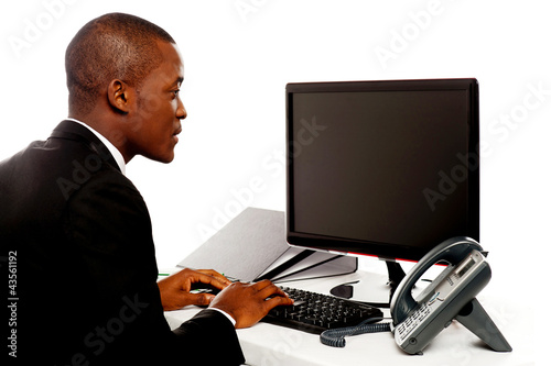 Photo: Male executive typing and looking at lcd screen Male executive typing and looking at lcd screen