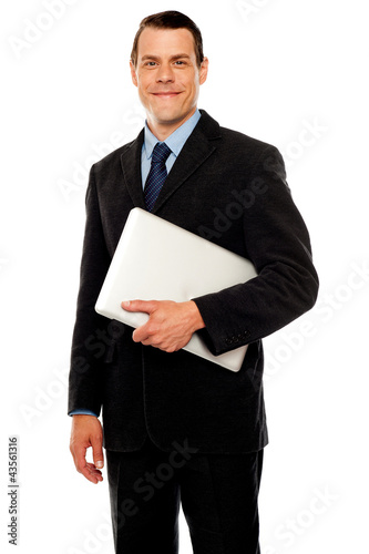 Photo: Handsome business executive holding laptop Handsome business executive holding laptop
