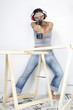 A woman with goggles and headphone using a driller to shoot at the camera