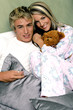 A couple in pajamas sitting together on the bed