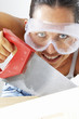 Close-up of a woman with goggles sawing a wood