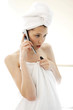 Foto: A woman with her hair and body wrapped up in towel talking on the hand phone in the bathroom A woman with her hair and body wrapped up in towel talking on the hand phone in the bathroom