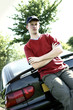 A boy with cap leaning against a car 