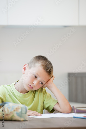 Photo: Tired/exhausted little boy with his homework Tired/exhausted little boy with his homework