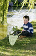Photo: Boy sitting by the river holding fishing net Boy sitting by the river holding fishing net