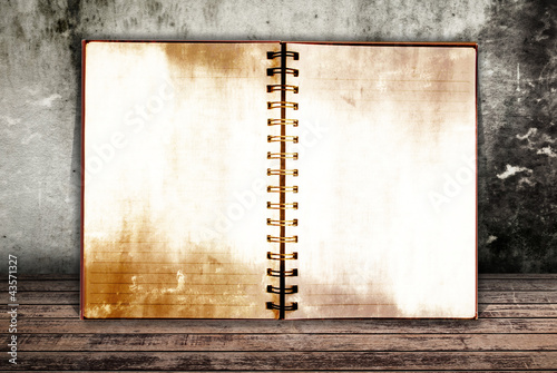 Photo: Grunge notebook on the wood wall. Grunge notebook on the wood wall.