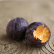 Close up of a bitten plum next to another plum