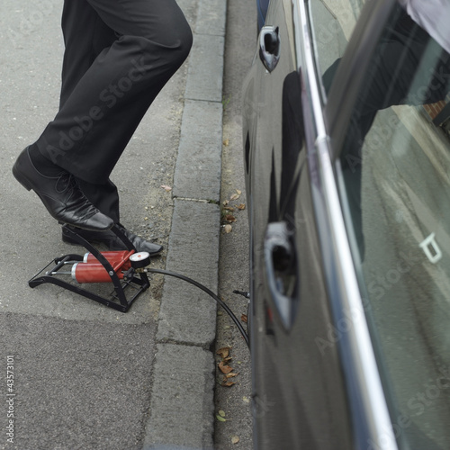 Photo: Businessman stepping on air pump Businessman stepping on air pump