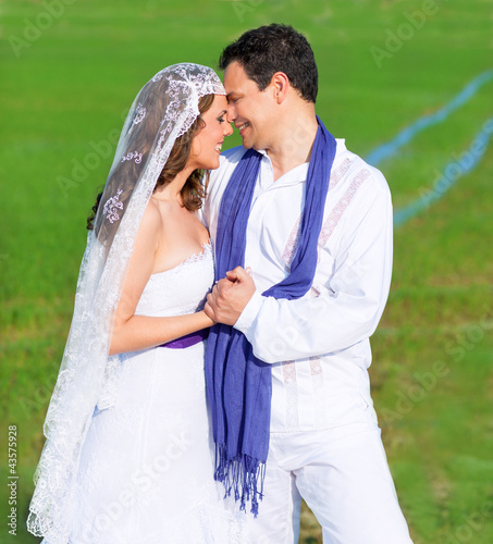 Photo: Couple in wedding day hug in green meadow Couple in wedding day hug in green meadow