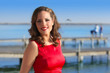Brunette woman dress in red smiling relaxed on a lake
