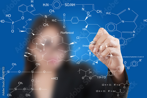 Photo: Teacher lady writing scientific formula on the whiteboard. Teacher lady writing scientific formula on the whiteboard.