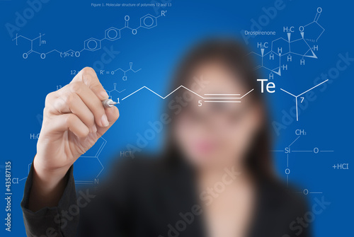 Photo: Teacher lady writing scientific formula on the whiteboard. Teacher lady writing scientific formula on the whiteboard.