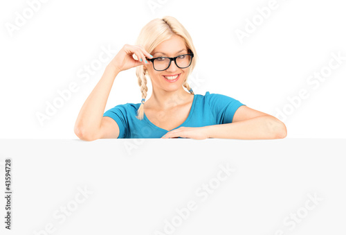 Foto: Young woman posing behind a blank panel Young woman posing behind a blank panel